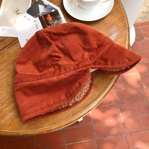 Close-up of a terracotta warm Sherpa-lined earflap hat on a rustic wooden table