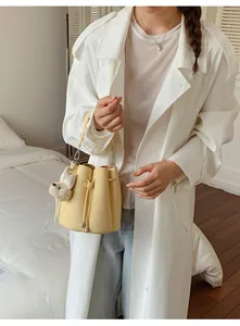 Detailed view of a stylish yellow leather bucket bag with a cute plush dog keychain.