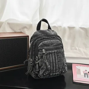 Close-up of vintage black denim backpack on a desk next to a stylish retro speaker