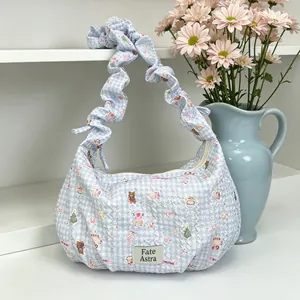 Detail view of a light blue checkered dumpling bag featuring a stylish ruffled shoulder strap