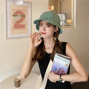 Asian female model wearing a stylish sage green ruffled edge bucket hat for sun protection