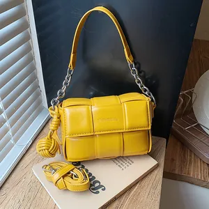 Detail shot showing the woven texture and silver chain of a yellow leather crossbody bag