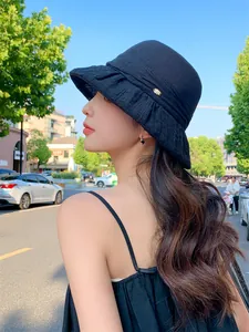 Detail of breathable black sun hat worn by a model in outdoor daylight