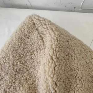 Close-up detail showing the soft beige sherpa fleece material texture of a winter hat