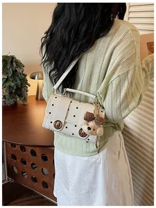 Detail view of a white polka dot retro handbag with a cute teddy bear plush charm.