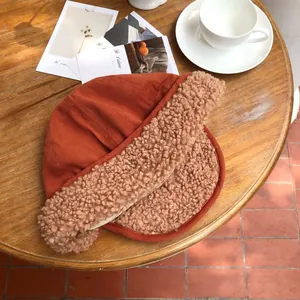 Detail shot of a warm orange winter hat featuring thick plush earflaps and soft lining