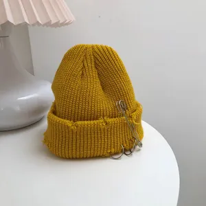 Close-up of yellow streetwear beanie with distressed edges and metal accessories