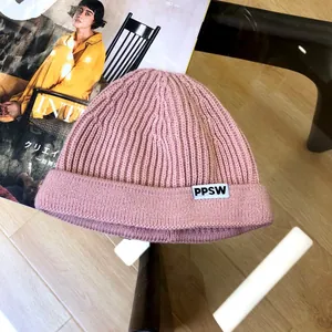Detailed macro shot of a stylish pink children's knitted beanie featuring a PPSW letter tag.