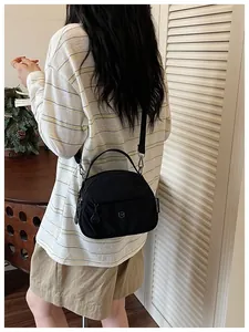 Vista detallada de un bolso bandolera de lona negra usado por una modelo femenina