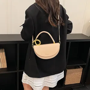 Detail einer minimalistischen beigen Satteltasche, getragen von einem Modell im schwarzen Blazer
