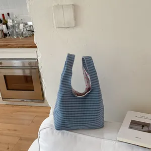 Minimalistische blau gestreifte Beuteltasche für Damen in gemütlichem Interieur