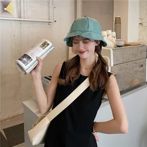 Close-up of a mint green wide-brim ruffle bucket hat worn by a female model in a cafe setting.