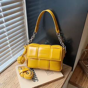 Detail view of a bright yellow woven underarm bag with silver chain and matching strap.