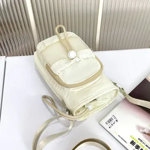 Detalle de cerca de un bolso bandolera para móvil en nylon acolchado crema con rejilla