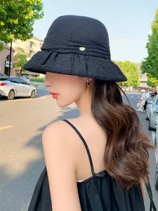 Side view of an elegant black bucket hat on a model showing ruffled brim and metal logo