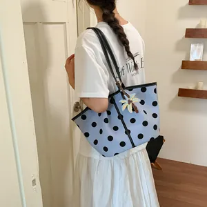 Model carrying a light blue polka dot tote bag with a tropical coconut tree charm