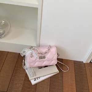Detailed shot of a pink quilted crossbody bag featuring a lace bow and pearl chain accent