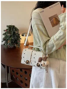 Model wearing a white vintage polka dot crossbody bag with a plush bear charm