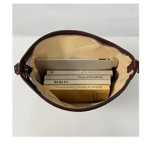 Binnenkant van bruine emmer tas met grote capaciteit met boeken en tablet erin.