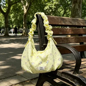 Floral yellow dumpling hobo bag with ruffled strap on a rustic park bench