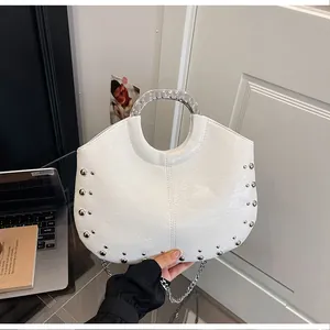 Detailed view of white minimalist handbag with silver studs and circular metal handle