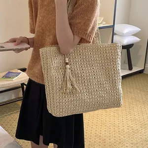 Vue détaillée d'un sac cabas en paille tissée avec un gland décoratif en perles de bois