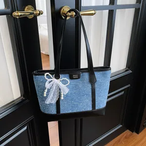 Sac cabas élégant en denim bleu avec nœud en dentelle et perles suspendu à la porte