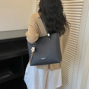 Lifestyle view of a woman carrying a black large capacity tote bag for daily commuting