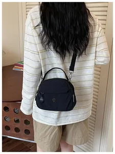 Vista trasera de una mujer con un bolso bandolera informal de lona negra para diario.