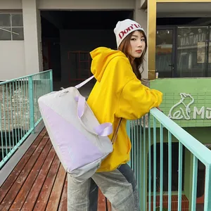 Close-up of stylish grey and purple color-block duffle bag carried by a fashion model