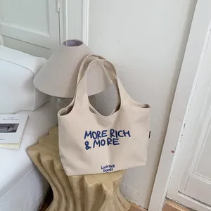 Elegante bolso tote de lona beige con bordado azul sobre una mesa decorativa