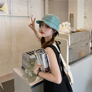 Asian female model wearing a stylish mint green pleated bucket hat in a modern cafe setting