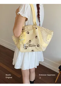 Detalle del bolso tote amarillo con lunares, huellas y un lindo amuleto de conejo