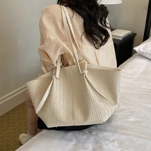 Elegant beige woven tote bag with high-quality texture shown in a lifestyle bedroom setting