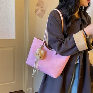 Close-up detail of a large pink tote bag with bear charm worn by a model in a coat