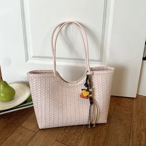 Vista detallada de la textura tejida rosa y el colgante de cuentas de colores en este bolso.