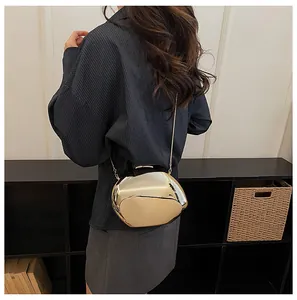 Vista styling di una chic borsa da sera dorata a specchio a forma di conchiglia con catena