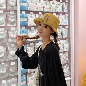 Stylish mustard yellow bucket hat with cute embroidered rabbit ears worn by a woman in a retail store