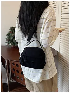 Bolso bandolera de tela negra para mujer mostrado por una modelo en una escena cotidiana