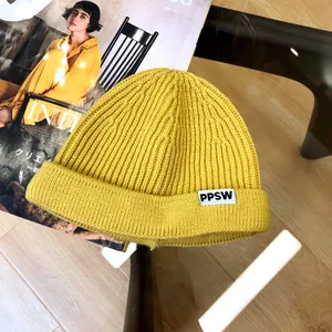 Detail shot of bright yellow knitted kids beanie with PPSW label and ribbed texture