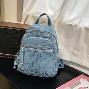 Detailed view of a stylish blue denim backpack for women in a lifestyle desk setup