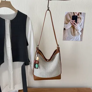 Detail of large capacity woven bucket bag with brown trim and colorful bead charm