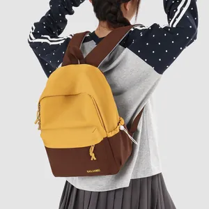 Detail view of the yellow and brown color-block college style backpack being worn