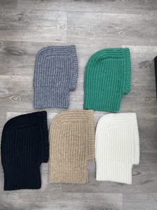 Five different colors of knitted hooded neck warmers on a grey wood floor