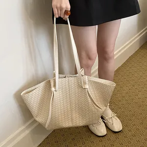 Close-up of beige woven fan-shaped tote bag showing textured detail and silhouette