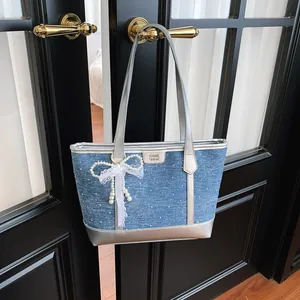 Vue détaillée d'un sac cabas en denim avec garniture argentée et nœud en perles