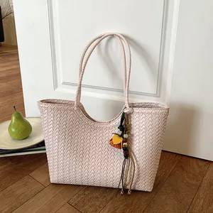 Primer plano detallado de la textura tejida y el colgante en el bolso rosa minimalista