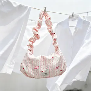 Detail view of pink striped quilted hobo bag with ruffled strap and strawberry motifs
