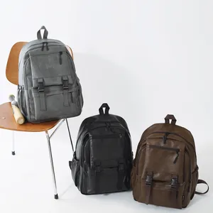 Trois sacs à dos vintage en similicuir gris noir et marron disposés sur une chaise.