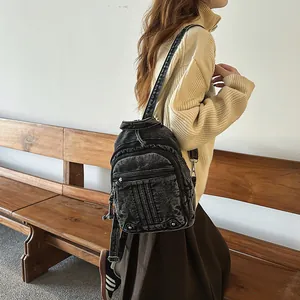 Detailed shot of vintage washed black denim backpack featuring multiple zipper pockets